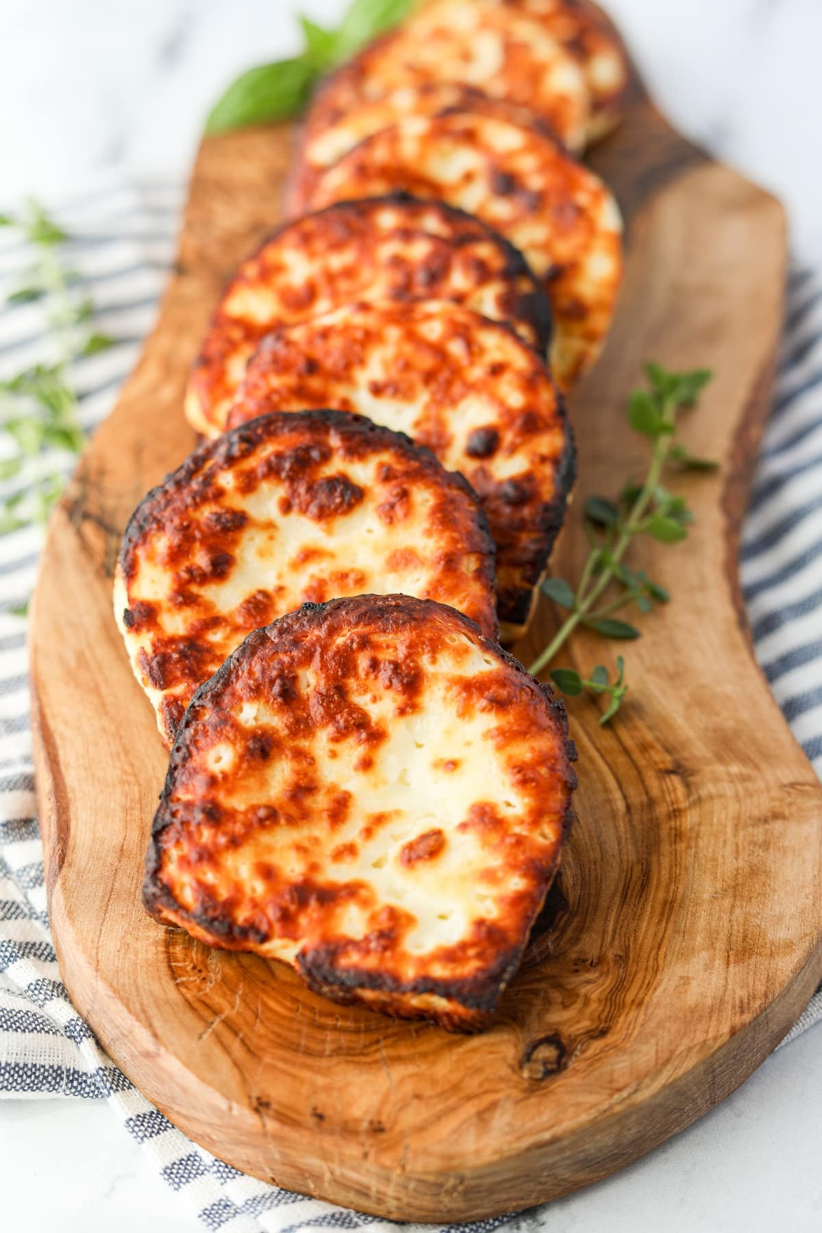 Slices of fried cheese on a wooden board.