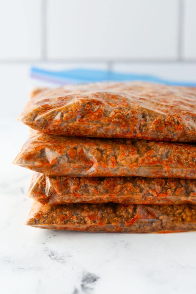 A stack of freezer bags filled with seasoned ground beef.