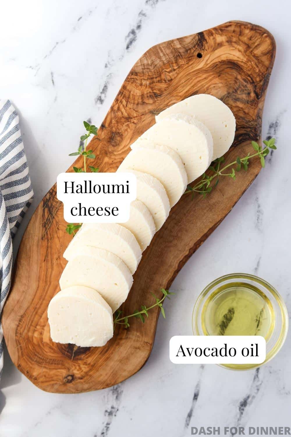 A wooden board with sliced halloumi and a small bowl of avocado oil.