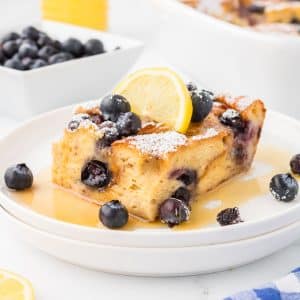 A square of baked French toast garnished with lemon and blueberries.