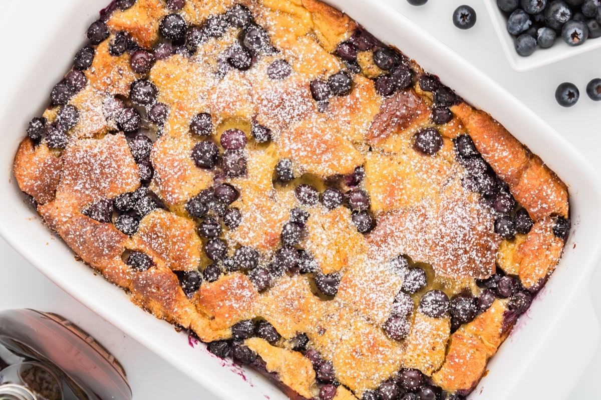 A French toast casserole garnished with blueberries and powdered sugar.