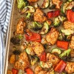 An air fryer tray filled with chicken pieces and vegetables.