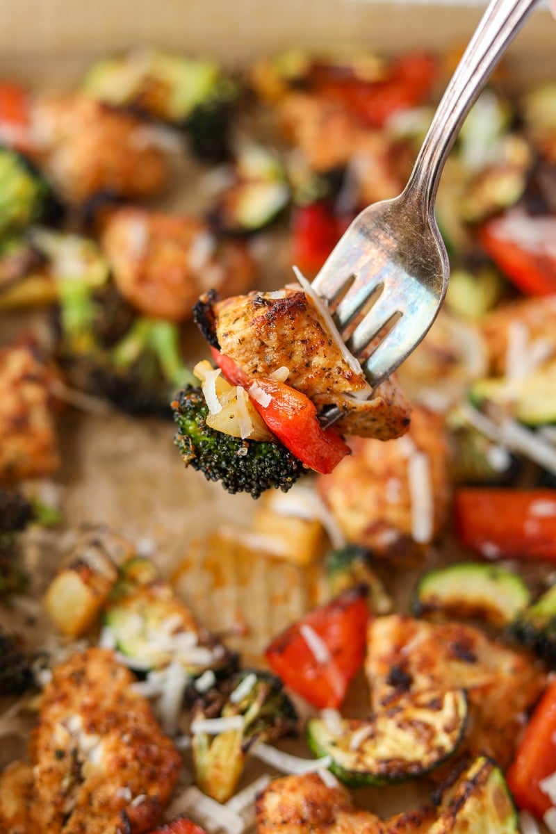 A fork taking a chunk of cooked chicken, a red pepper, and broccoli.