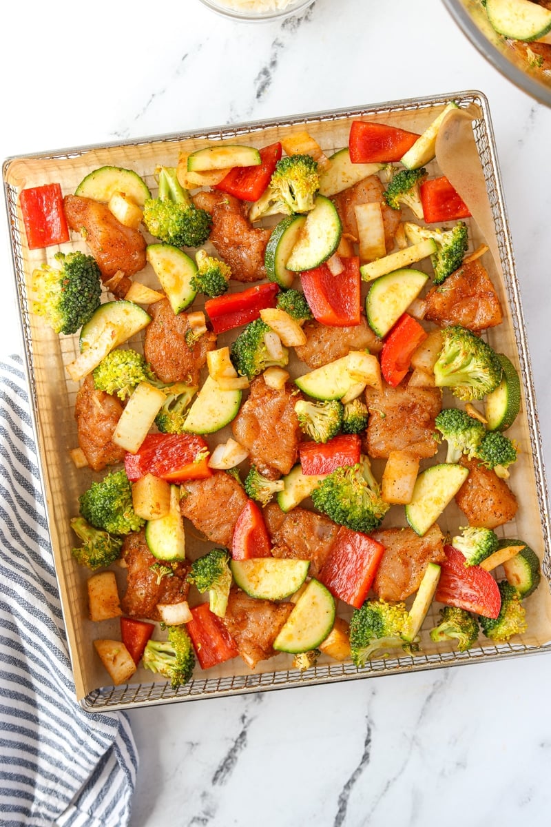 An air fryer tray filled with chicken and vegetables.