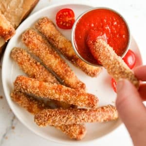 Dipping a breaded halloumi fry into pizza sauce.