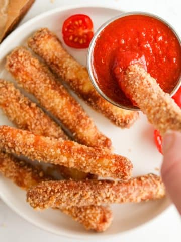 Dipping a breaded halloumi fry into pizza sauce.