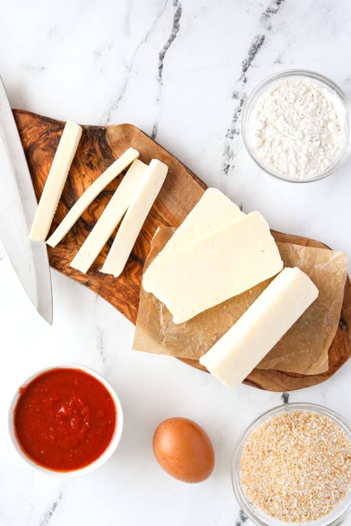 A cutting board with cheese cut into sticks.