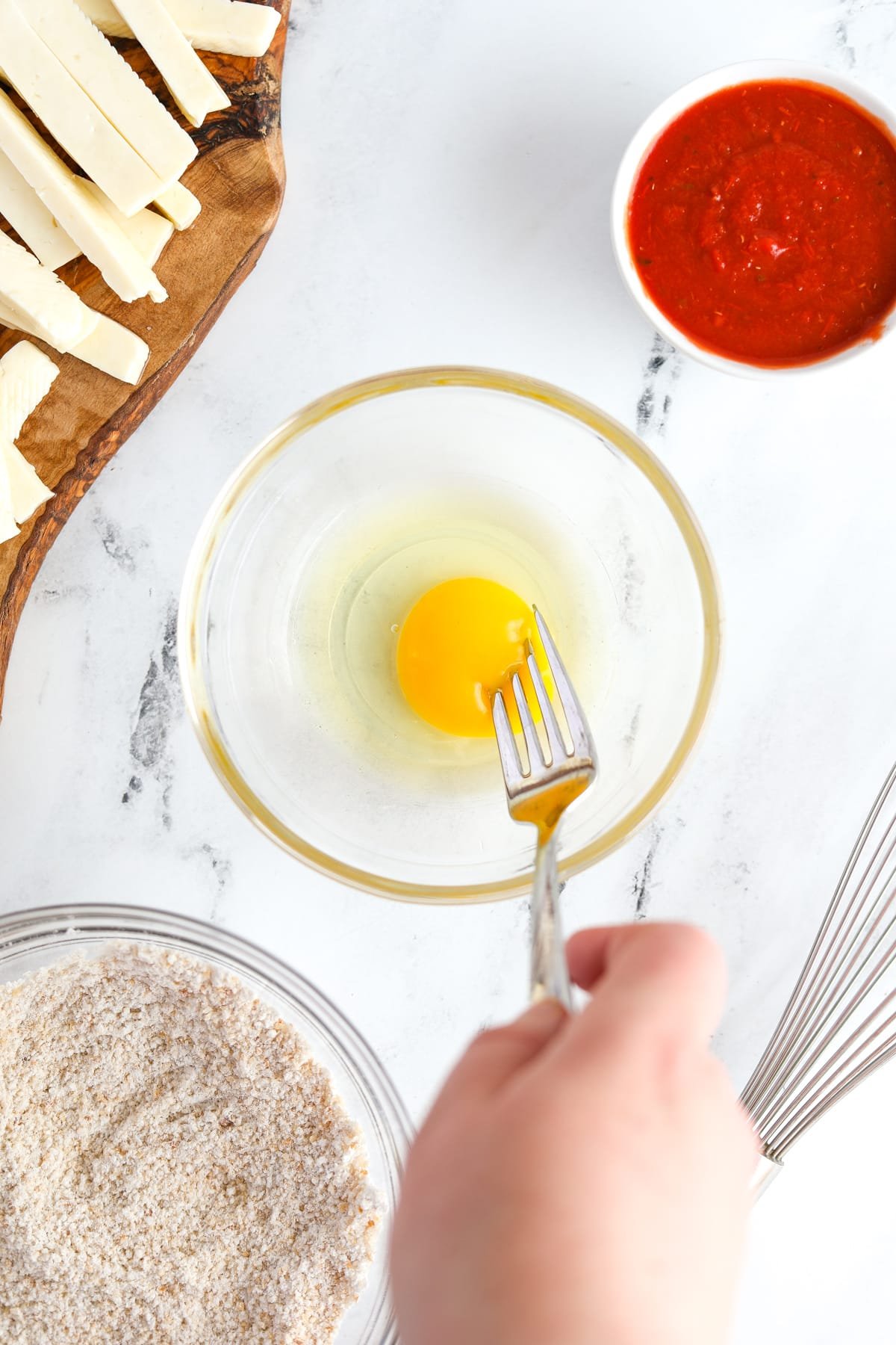Whisking an egg in a small bowl.