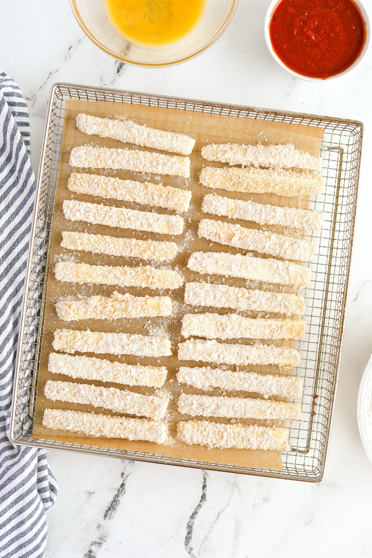 Breaded halloumi sticks on an air fryer tray.