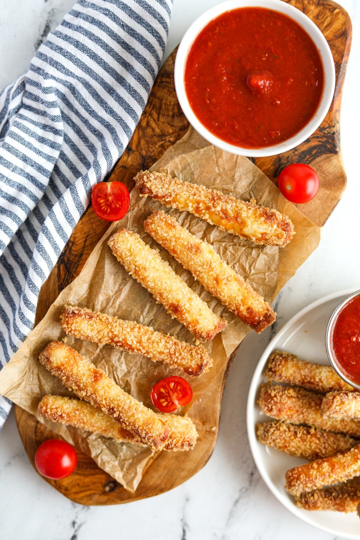 A wooden platter filled with halloumi fries and a small bowl of pizza sauce.