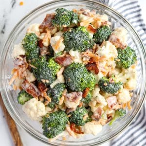 A bowl of broccoli salad garnished with cheese and bacon.