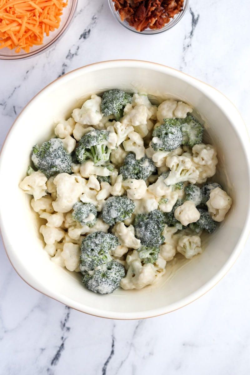 A bowl of broccoli and cauliflower dressed with a creamy sauce.