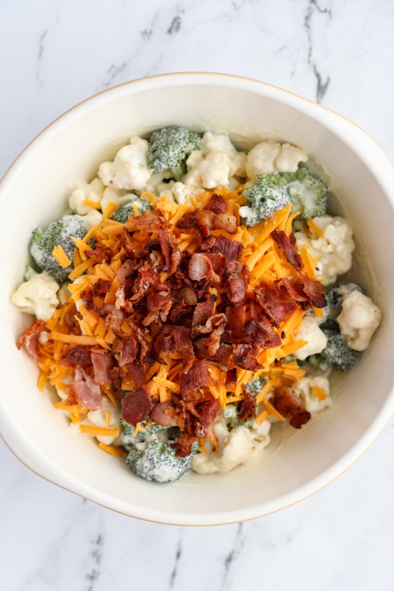 A bowl of broccoli salad with cheese and bacon on top.