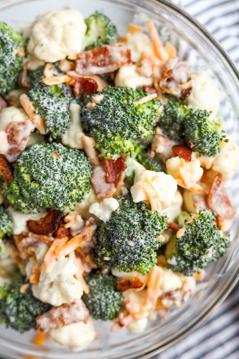 A close up of a bowl of broccoli salad with cheese and bacon.