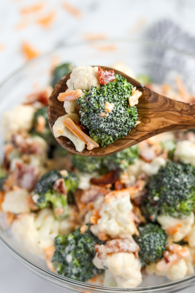 A serving of broccoli salad on a wooden spoon.