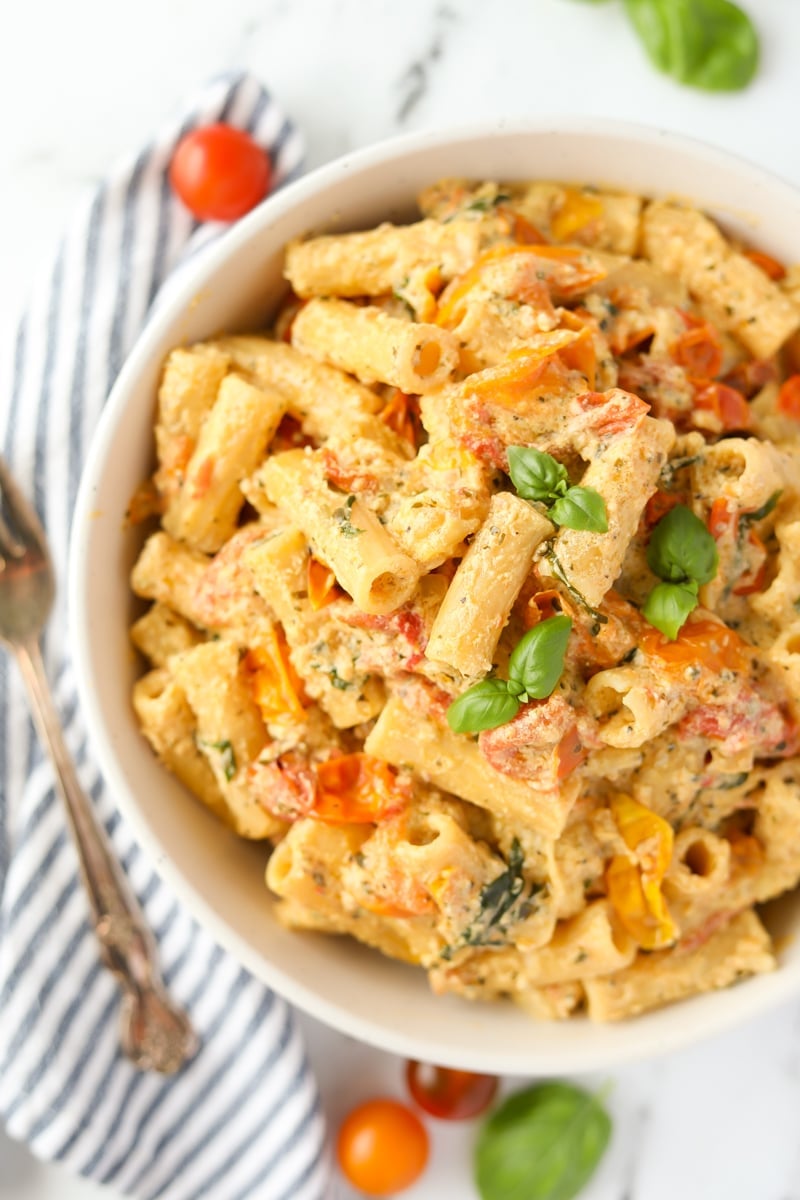 A bowl of pasta garnished with basil.