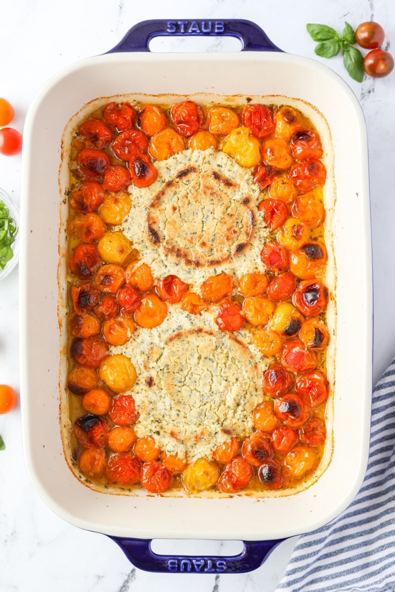 A baking dish with roasted cherry tomatoes and blistered cheese.