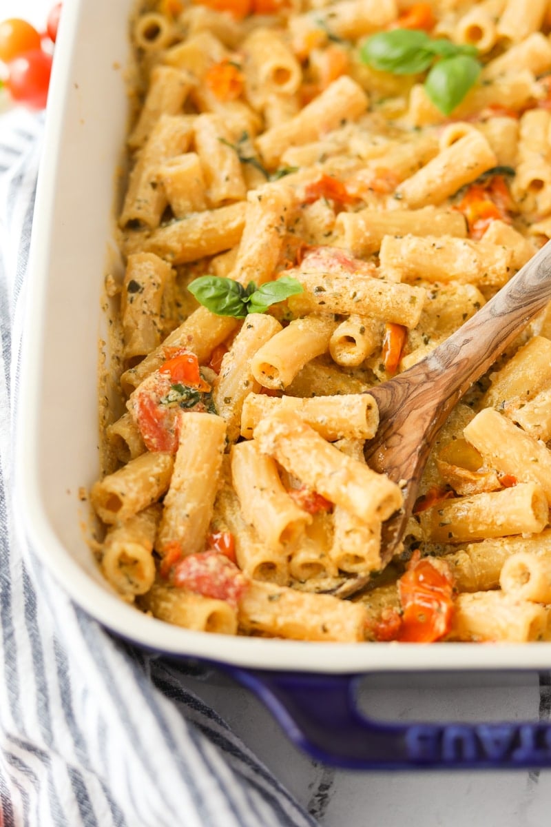 A spoon taking a portion of pasta with a creamy sauce.