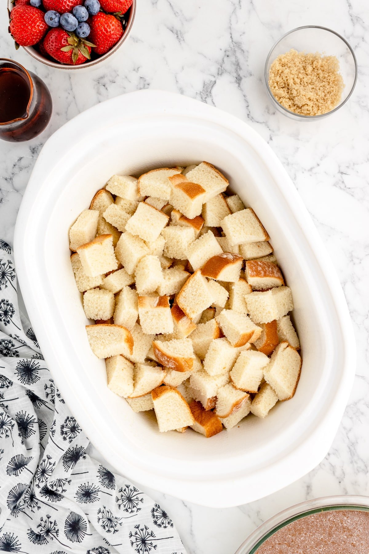 A slow cooker filled with bread cubes in it.