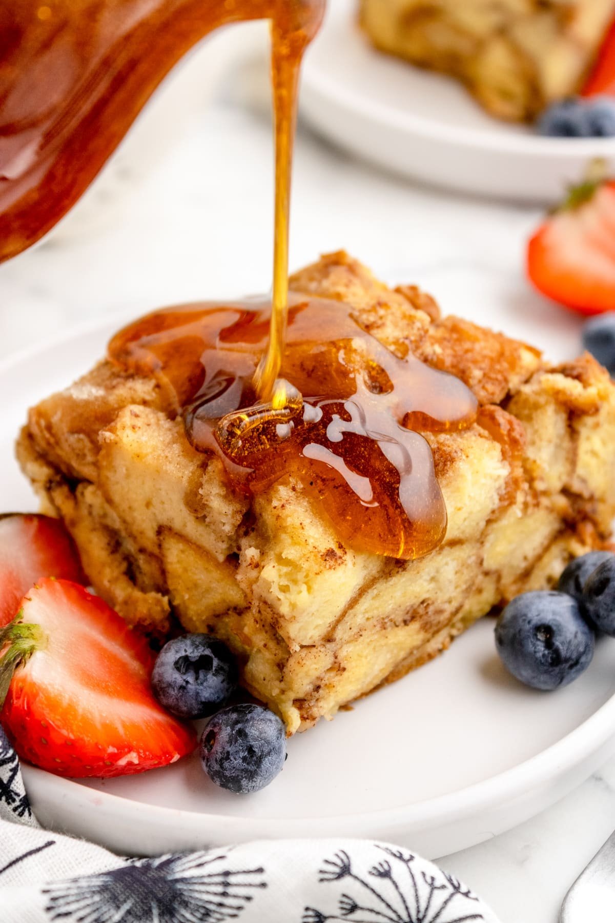 A square of French toast casserole drizzled with maple syrup.