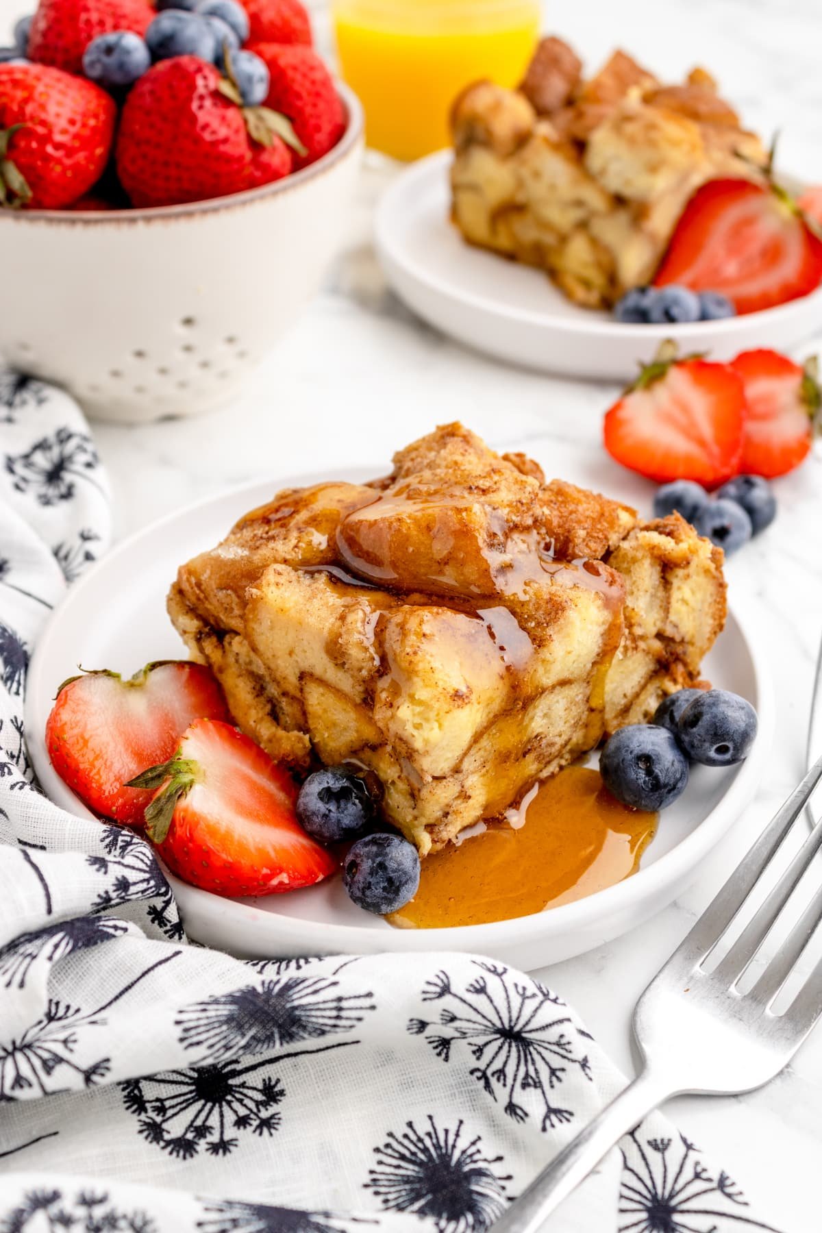 A square of French toast drizzled with maple syrup and garnished with berries.