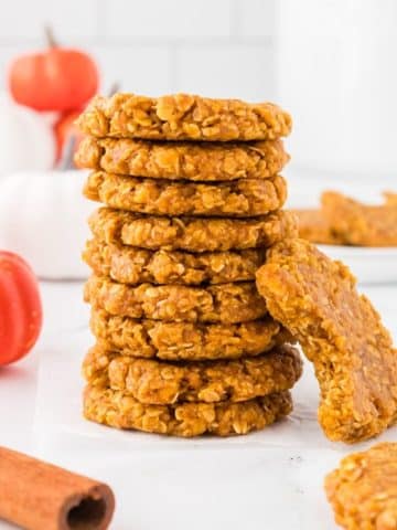 A stack of pumpkin no bake cookies, one with a bite taken out of it,.