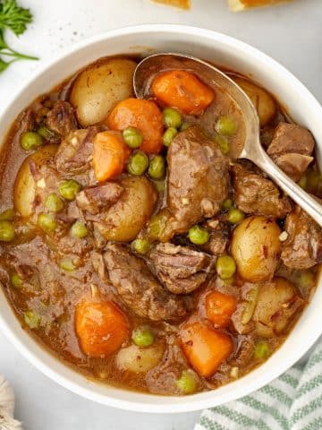 A bowl of beef stew with a spoon inside.