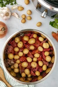 An Instant Pot filled with beef cubes, and topped with baby potatoes.