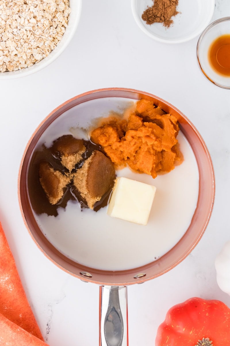 A saucepan with milk, brown sugar, pumpkin, and butter inside.