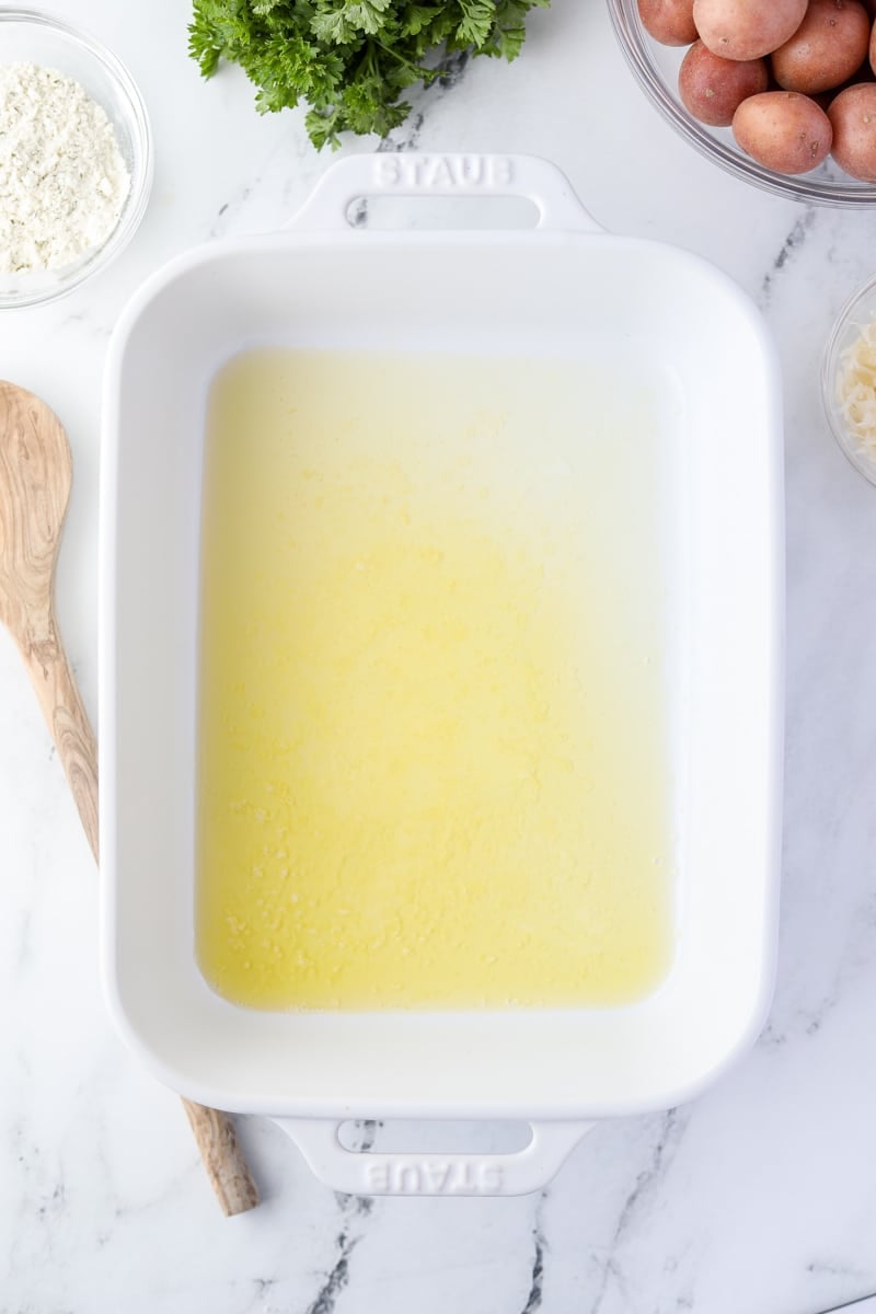 A white baking dish with melted butter.
