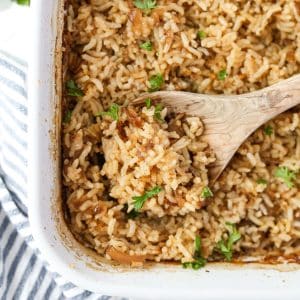 Scooping a portion of rice from a baking dish.