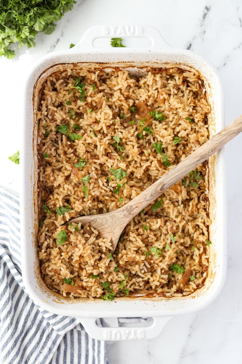 A baking dish filled with rice and garnished with parsley.