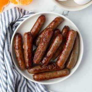 A small plate filled with cooked breakfast sausages.