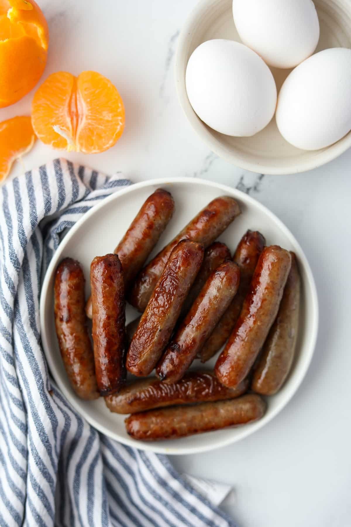 A plate of cooked breakfast sausages on a marble counter.