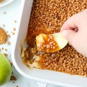 Dipping an apple slice into a caramel and cream cheese dip.