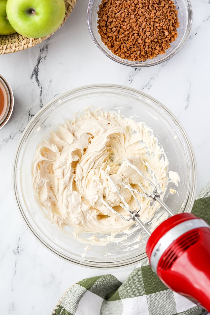 Mixing together cream cheese with a hand mixer.