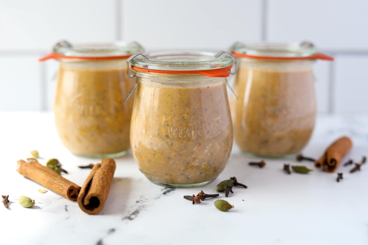 Three jars filled with pumpkin overnight oatmeal, resting on a countertop.