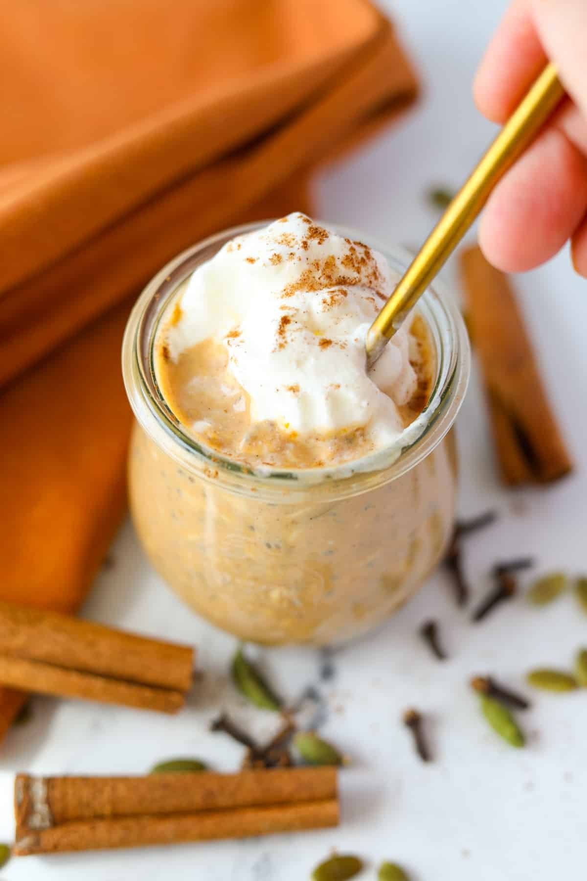 A spoon taking a portion from a jar of pumpkin overnight oatmeal.