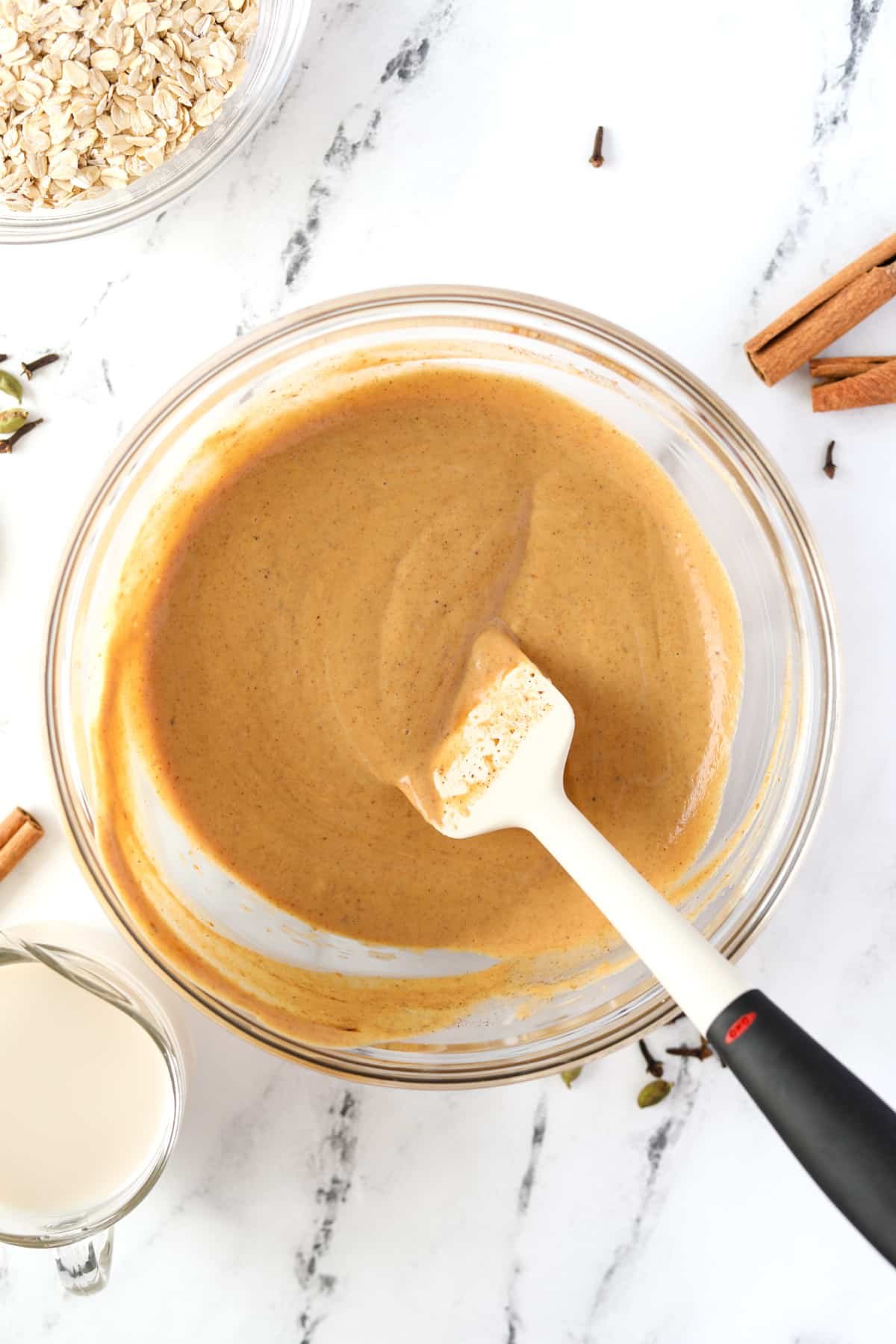 A silicone spatula stirring a pumpkin colored liquid.