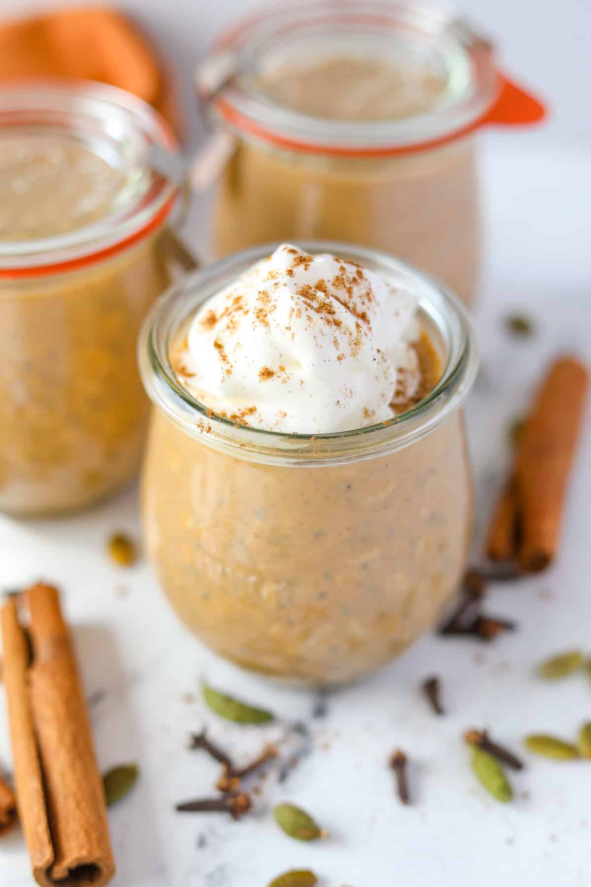 A small jar of pumpkin overnight oatmeal, garnished with whipped cream.