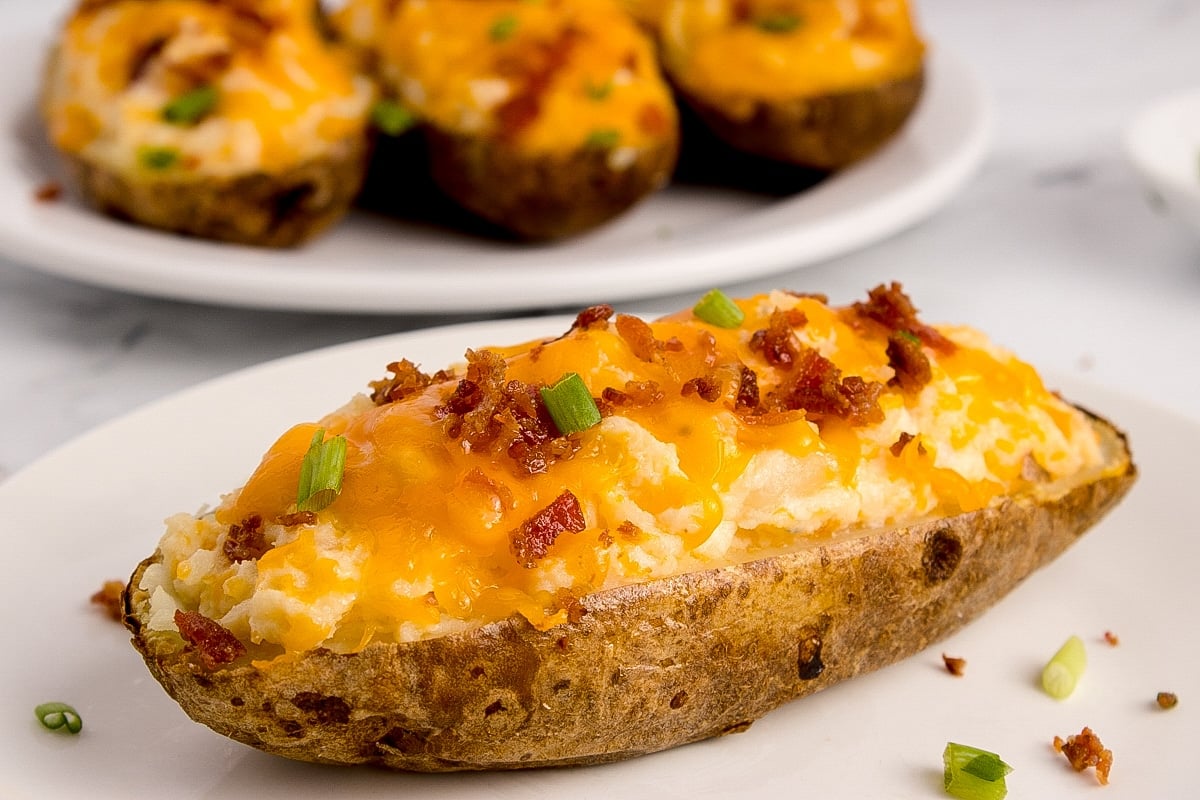 Half of a stuffed potato, topped with bacon and cheese.
