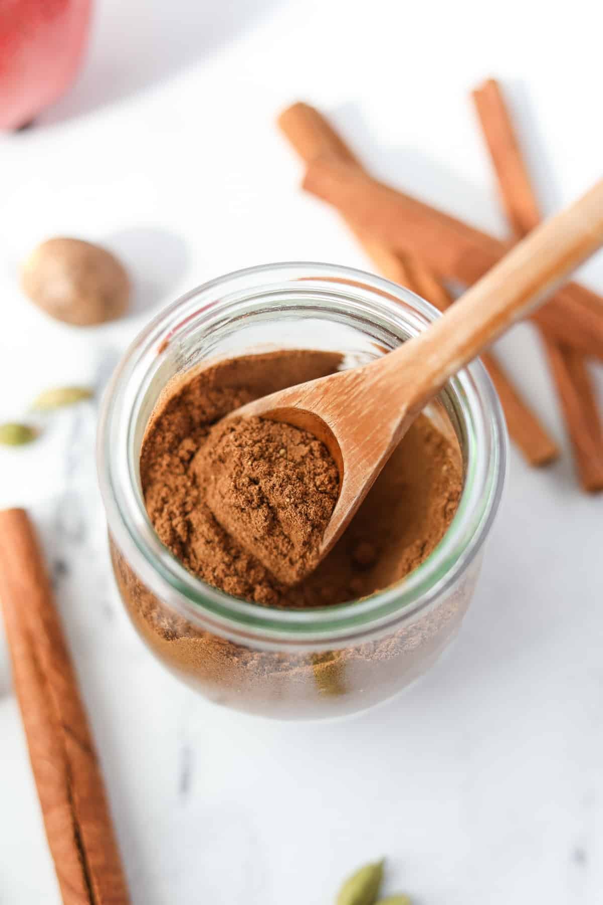 A small spoon taking a portion of apple spice from a jar.