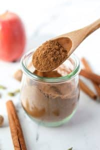 Using a spoon to take apple pie spice from a jar.