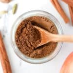 A small jar with a homemade spice blend and a wooden spoon inside.