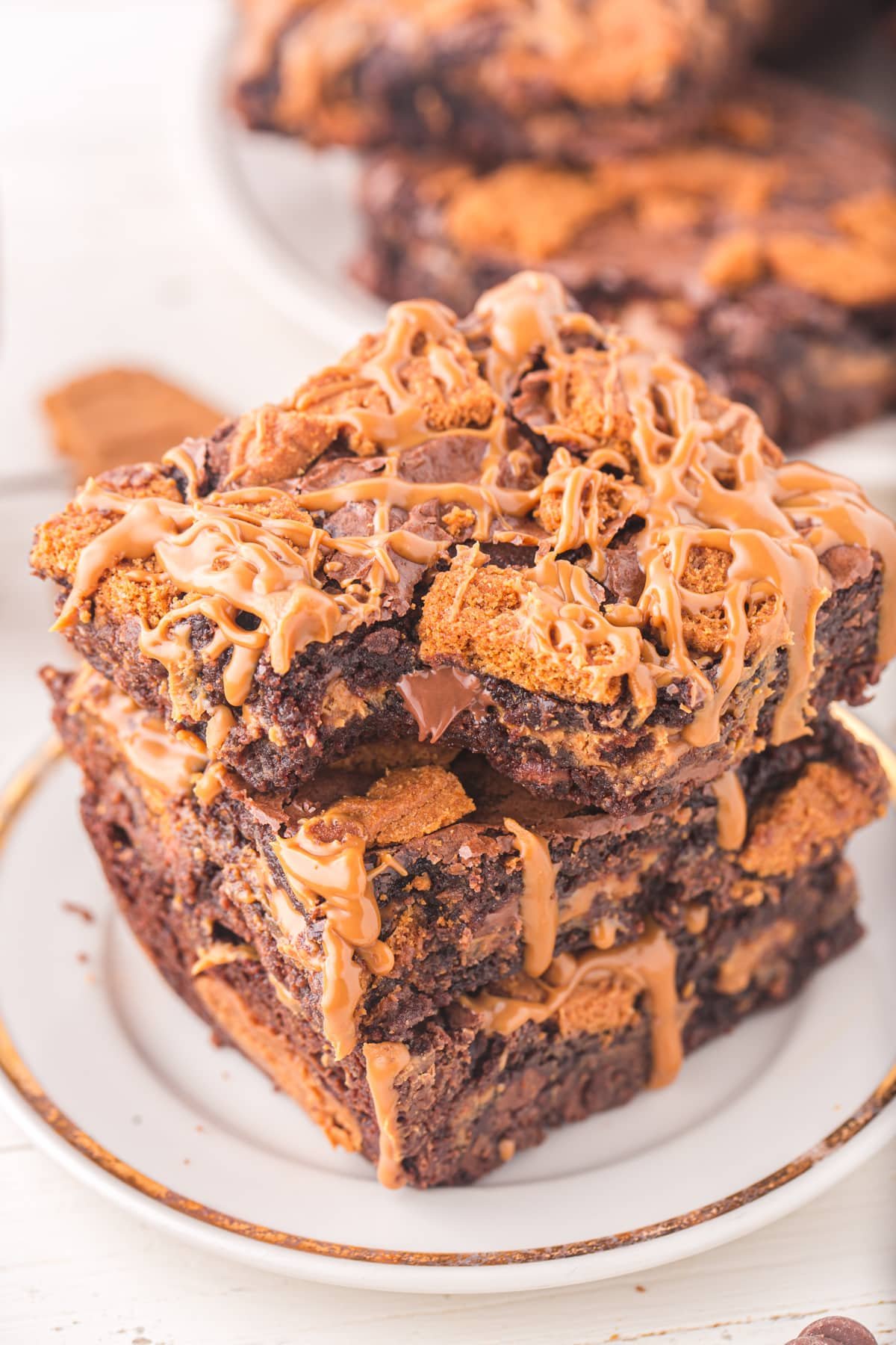 A stack of three brownies topped with crushed Biscoff cookies and cookie butter.