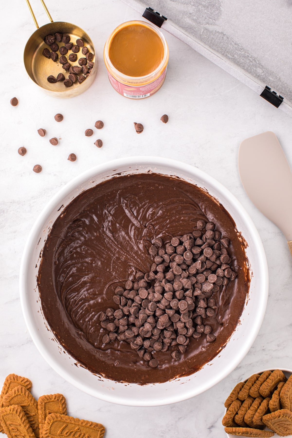 A bowl of brownie batter with chocolate chips added into the batter.