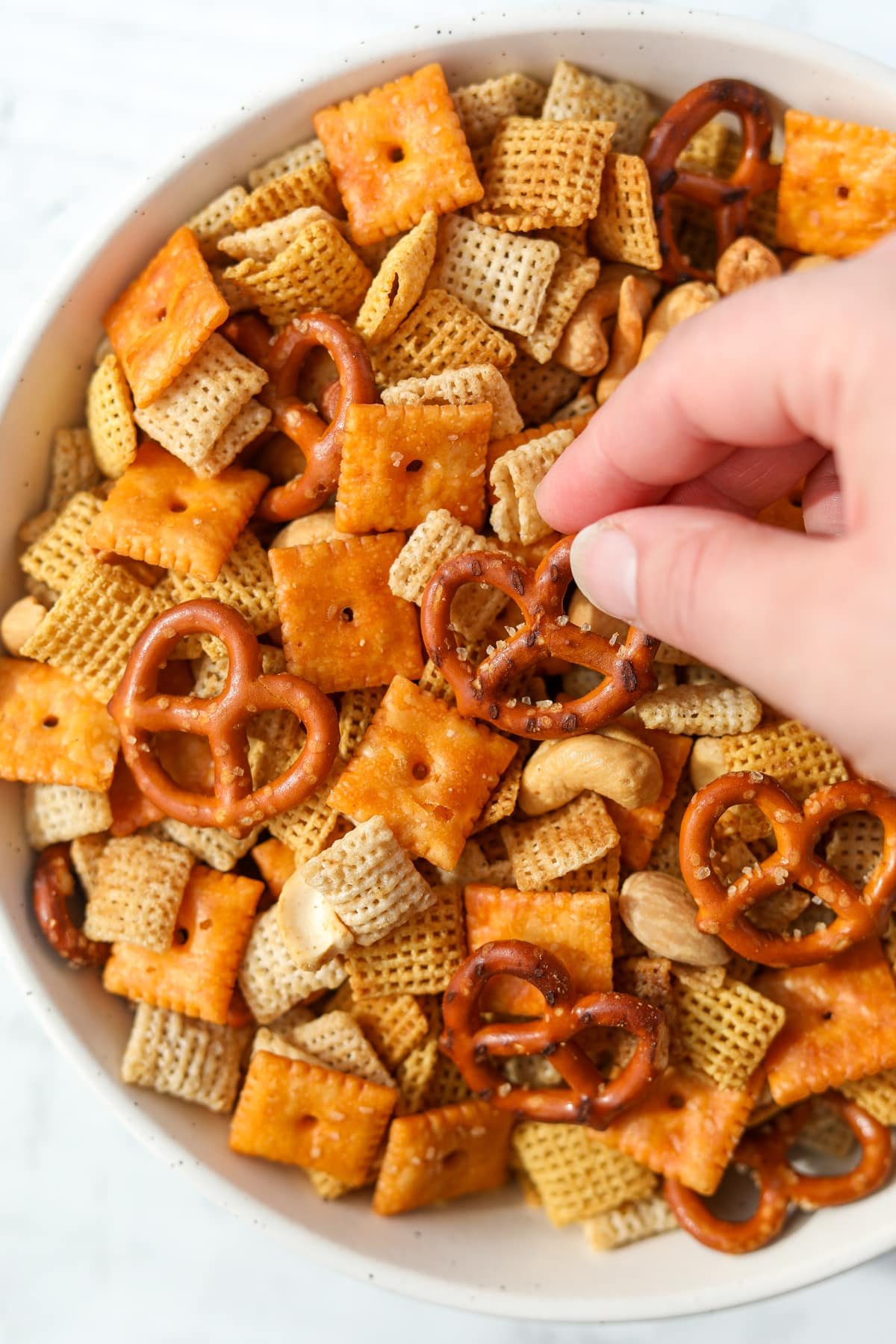 Taking a pretzel from a bowl of snack mix.
