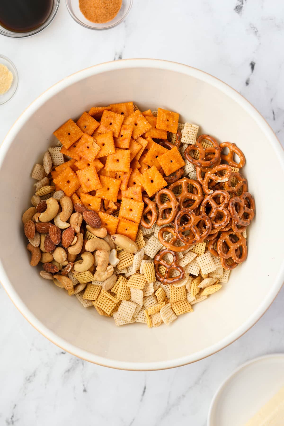 A bowl with cheese crackers, Chex mix, pretzels, and mixed nuts.