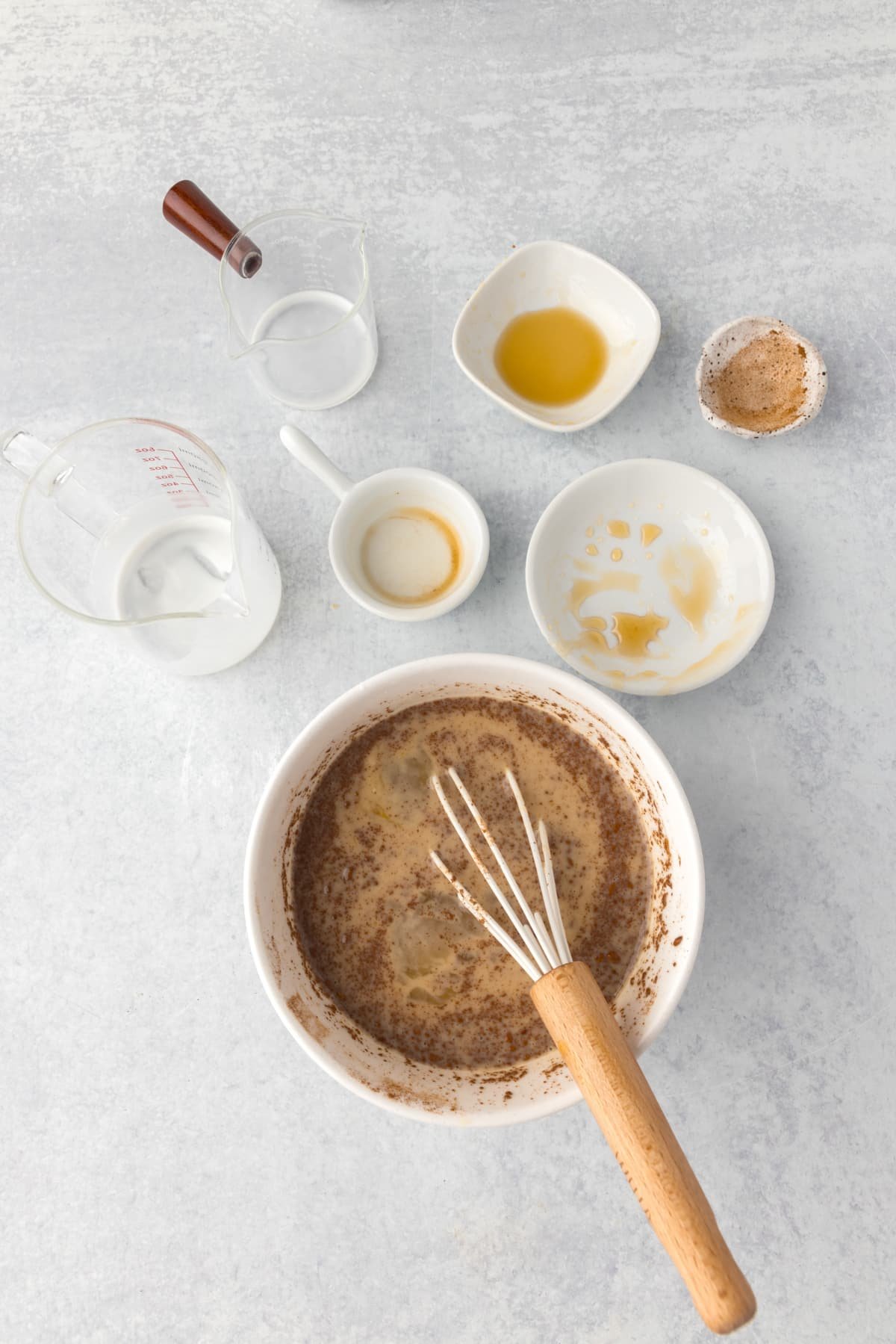 Whisking together ingredients in a bowl, with empty cups and bowls surrounding it.