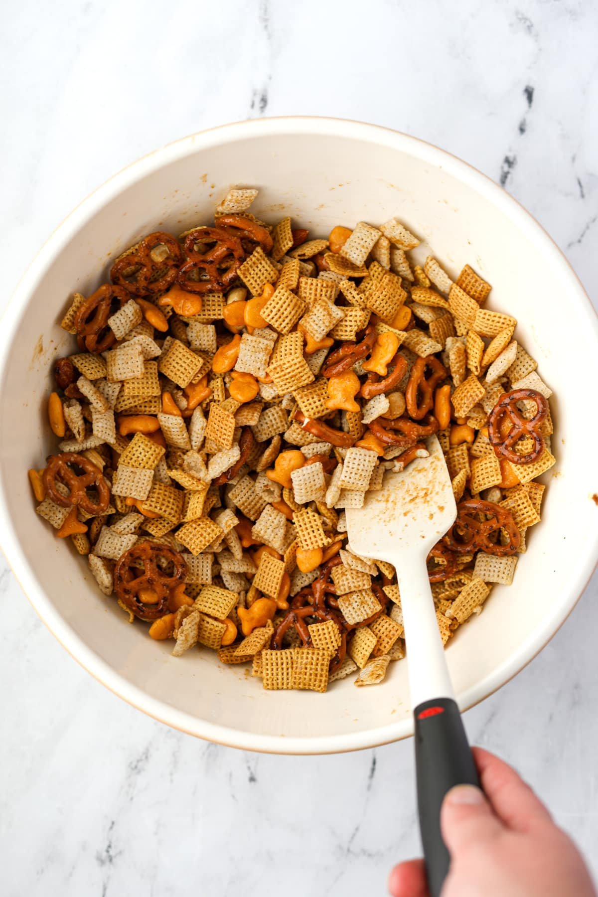 Mixing together a homemade snack mix in a large bowl.